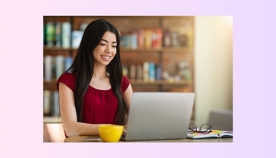 A woman checks her laptop screen with a relaxed smile.