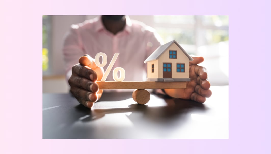 An image of a man holding a balance, with a percentage sign on one end and a small toy house on the other.