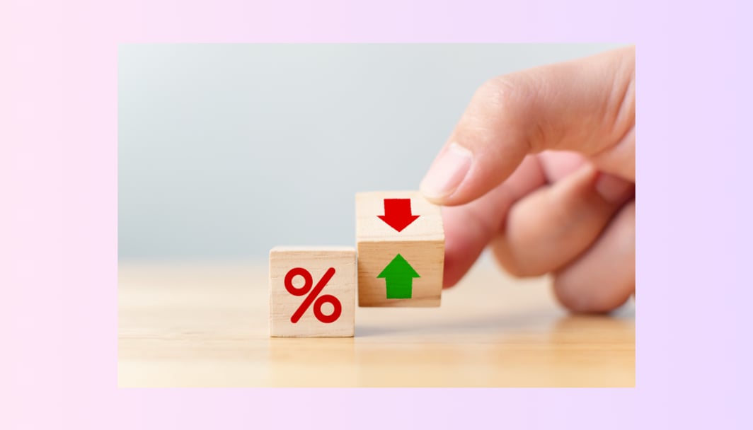 An image of a hand holding two wooden blocks with a percentage sign and red and green arrows.