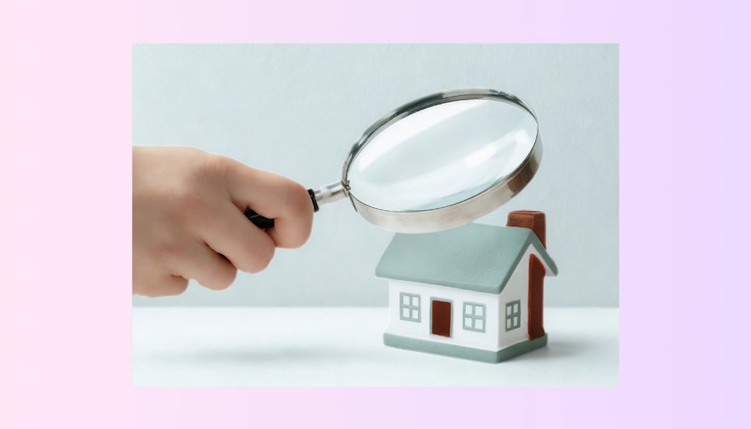 A person holding a lens over the model of a house representing the title 'property valuations'