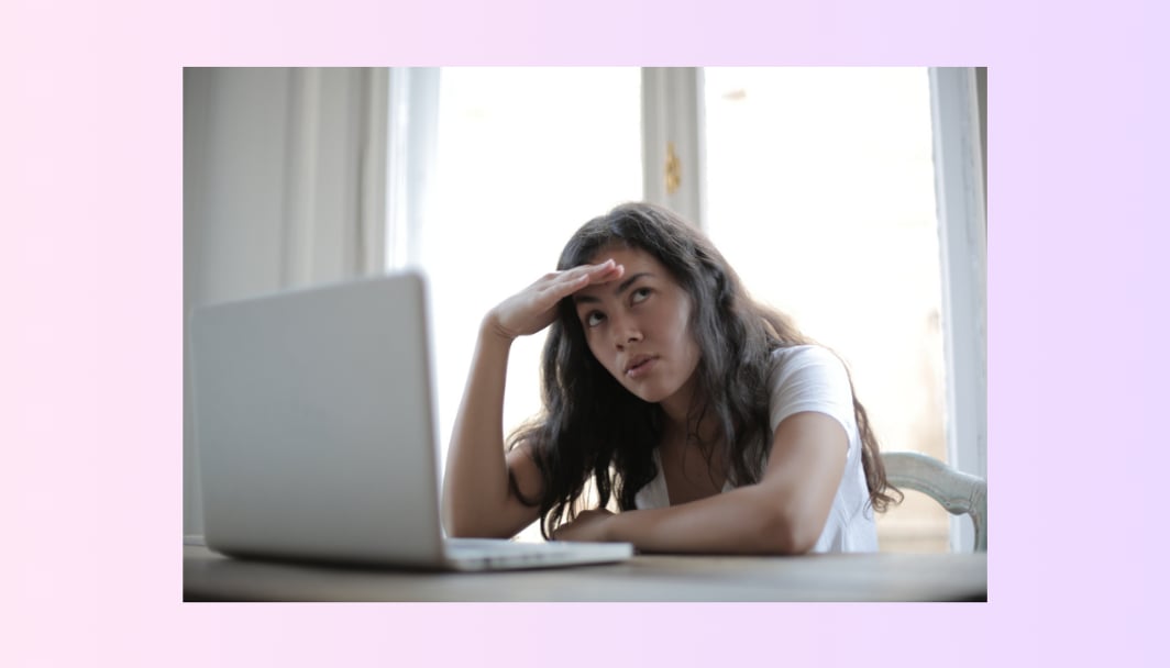 A woman looking away from her screen with a confused expression.
